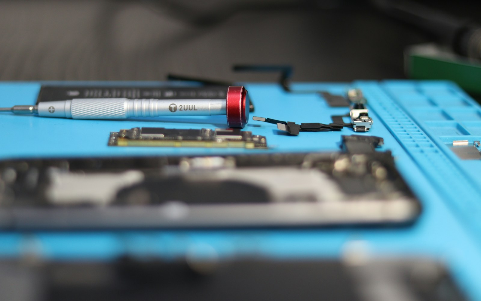 Phone repair tools lay on a blue mat