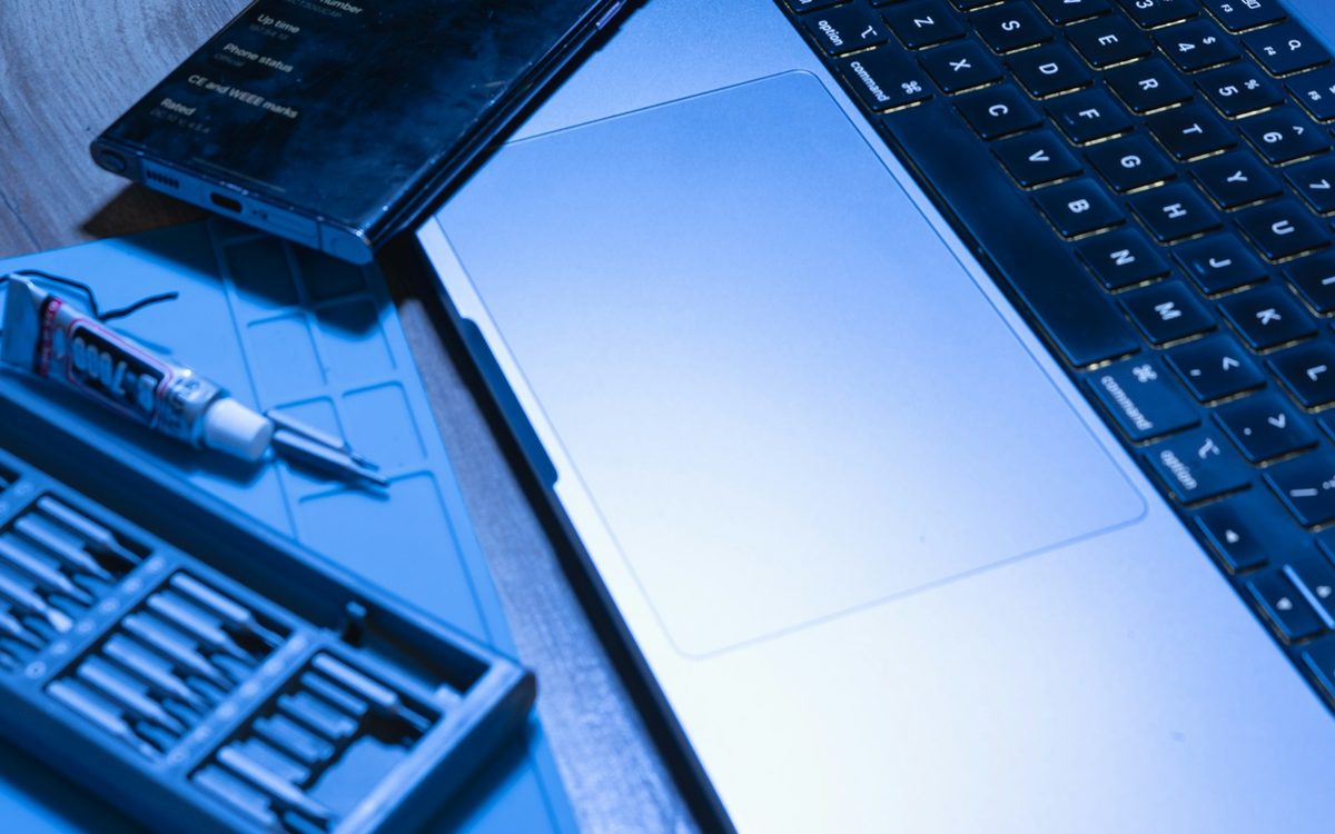 Laptop, smartphone, and repair tools on a desk